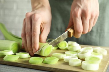 Gri ahşap masada pırasa kesen kadın, yakın plan.