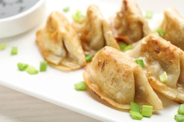 Kızarmış gyoza köftesi, yeşil soğanlı ve soya soslu, beyaz masada, yakın plan.