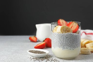 Çilekli lezzetli chia pudingi ve açık gri masada muz, metin için yer var.