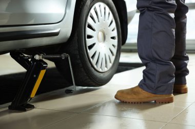 Makas kriko ile kaldırılan araba. Servis istasyonunda otomatik tamirci tamir aracı, kapatılıyor