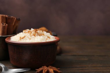 Ahşap masada servis edilen tarçınlı lezzetli sütlaç, yakın plan. Metin için boşluk