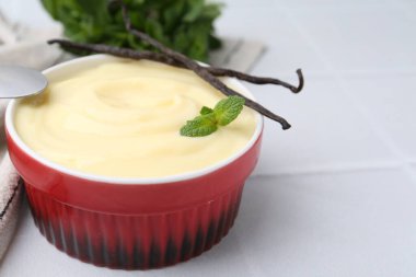 Lezzetli vanilyalı puding, nane ve kapsüller beyaz fayanslı masada, yakın plan. Metin için boşluk