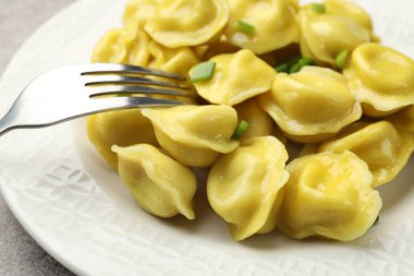 Gri desenli masada yeşil soğan ve çatallı lezzetli hamur tatlısı, yakın plan.