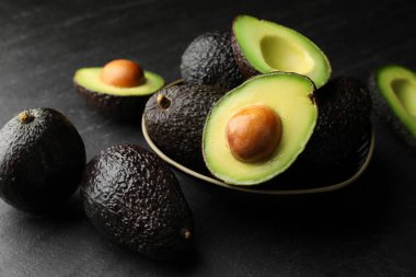 Avokadoların tamamı koyu dokulu masa üzerinde, yakın plan.