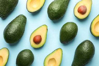 Avokadoların tamamı ve kesimi açık mavi arka planda, düz yatıyordu