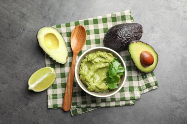 Lezzetli avokado sosu, maydanoz ve meyveler gri masada, düz yerde.