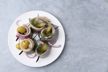 Gri desenli masada zeytinli, turşulu, dereotlu ve soğanlı lezzetli ringa dürümleri. Metin için boşluk