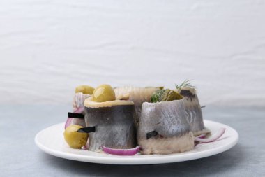 Zeytinli, turşulu, dereotlu ve soğanlı lezzetli ringa dürümleri gri masada, arka planda, yakın plan