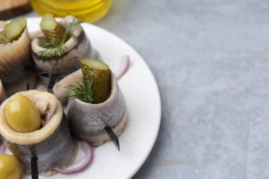 Gri desenli masada zeytinli, turşulu, dereotlu ve soğanlı lezzetli ringa dürümleri, yakın plan. Metin için boşluk