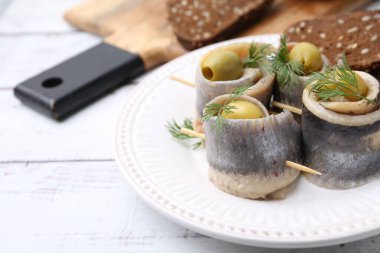 Zeytinli lezzetli ringa dürümleri, beyaz ahşap masada dereotu ve ekmek, yakın plan. Metin için boşluk