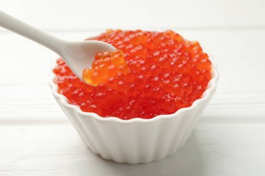 Lezzetli kırmızı havyarı beyaz ahşap masada kaşıktan kaşığa alıp yakın plan çekiyoruz.