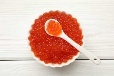 Lezzetli kırmızı havyar kasede ve kaşıkla beyaz ahşap masa, üst manzara