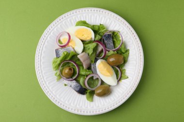 Ringa balıklı lezzetli salata, yeşil arka planda yumurta ve sebzeler, üst manzara.