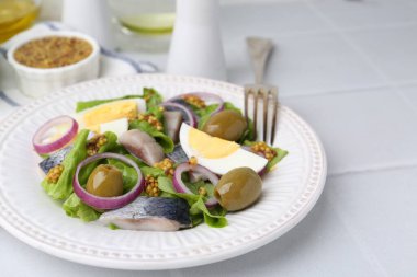 Ringa balıklı lezzetli salata, yumurta, hardal ve sebzeler beyaz fayanslı masada, yakın plan.