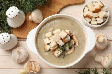 Lezzetli mantar kremalı çorba, kızarmış ekmek, dereotu ve malzemeler beyaz ahşap masa üzerinde, düz yatıyordu.