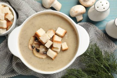 Lezzetli mantar kremalı çorba, kızarmış ekmek ve malzemeler mavi masada.