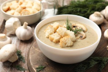 Lezzetli mantar kremalı çorba, kızarmış ekmek, dereotu ve ahşap masa malzemeleri, yakın plan.