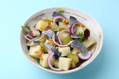 Ringa balıklı lezzetli salata, sebze ve açık mavi arka planda hardal, yakın plan.