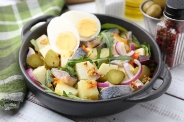 Ringa balıklı lezzetli salata, yumurta ve sebzeler beyaz ahşap masada servis edilir, yakın plan.