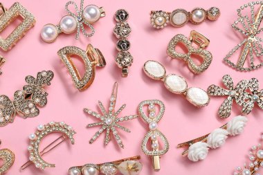 Different hair clips on pink background, flat lay