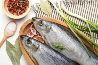 Tuzlu ringa balıkları ve baharatlar beyaz ahşap masada, düz yatıyordu.