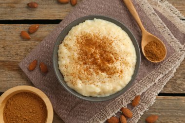 Tarçınlı lezzetli sütlaç ve ahşap masada badem.