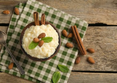 Tahta masada servis edilen bademli, nane ve tarçınlı lezzetli sütlaç.