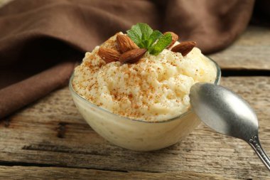 Tarçınlı lezzetli sütlaç, badem ve nane, ahşap masada servis edilir, yakın plan.