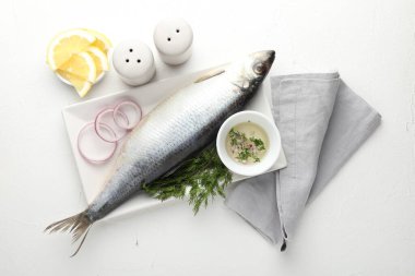 Tuzlu ringa balığı ve baharatlar beyaz masada, düz yerde.