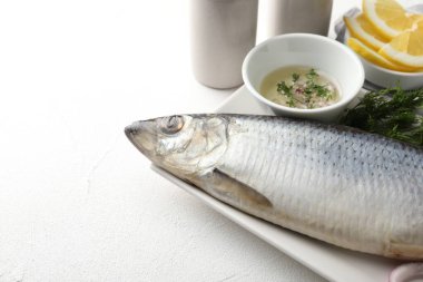 Tuzlu ringa balığı ve baharatlar beyaz masada, yakın plan. Metin için boşluk