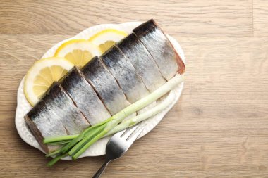 Limon dilimleri ve ahşap masada yeşil soğanlı lezzetli ringa balıkları. Metin için boşluk