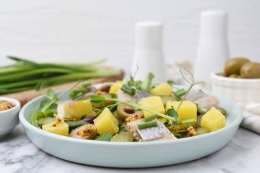 Ringa balıklı lezzetli salata ve beyaz mermer masada malzemeler, yakın plan.