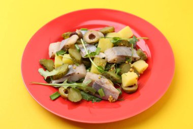 Sarı arka planda ringa balığı olan lezzetli salata, yakın plan.