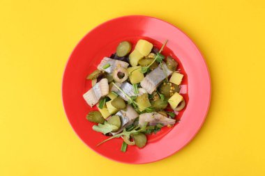 Sarı arka planda ringa balıklı nefis salata.