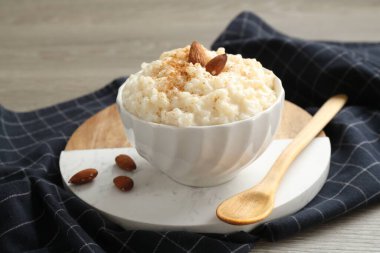 Tarçınlı lezzetli sütlaç, badem ve kaşık ahşap masada, yakın plan.