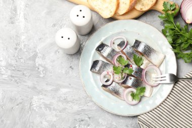 Gri desenli masada servis edilen baharat ve soğanlı lezzetli ringa balıkları. Metin için boşluk