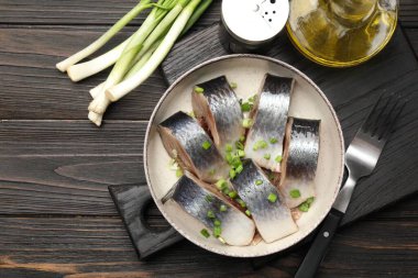 Lezzetli ringa balıkları. Yeşil soğanlı. Siyah ahşap masada servis ediliyor.