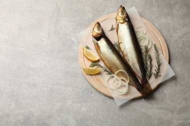 Açık gri masada tütsülenmiş ringa balığı, soğan, biberiye ve limon. Metin için boşluk