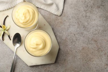 Lezzetli vanilyalı puding, kapsüller ve çiçek gri masada, düz yerde. Metin için boşluk