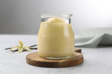 Lezzetli vanilyalı puding, kapsüller ve çiçek gri masada, yakın plan.