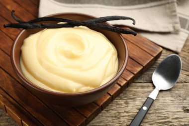 Tahta masada servis edilen lezzetli vanilyalı puding ve kapsüller.