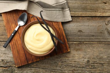 Lezzetli vanilyalı puding ve kapsüller ahşap masada, düz yerde. Metin için boşluk