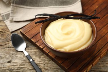 Tahta masada servis edilen lezzetli vanilyalı puding ve kapsüller.