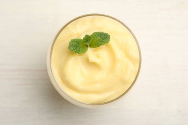 Beyaz ahşap masada naneli vanilyalı puding.