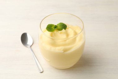 Beyaz ahşap masada servis edilen naneli vanilyalı puding.