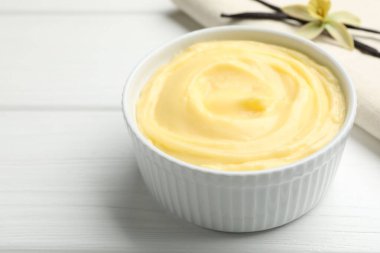 Lezzetli vanilyalı puding ve kapsüller beyaz ahşap masada, yakın plan.