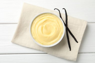 Lezzetli vanilyalı puding ve beyaz ahşap masadaki kapsüller.