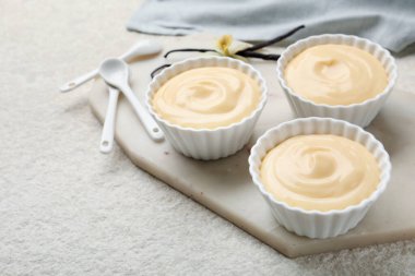 Kaşıklar, kapsüller ve çiçekli lezzetli vanilyalı puding açık dokulu masa, yakın çekim.