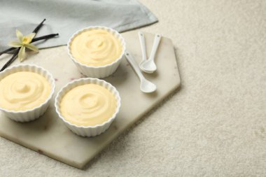 Kaşıklar, kapsüller ve çiçek desenli açık masalı lezzetli vanilyalı puding. Metin için boşluk