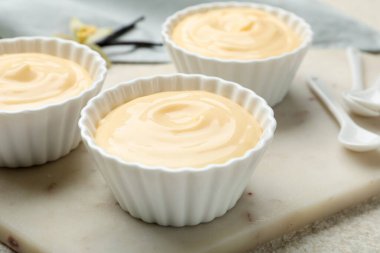 Hafif desenli masada kaşıkları olan lezzetli vanilyalı puding, yakın plan.